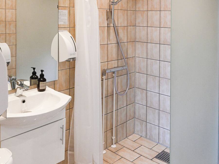 A bathroom with a sink, mirror, and shower area.