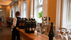 A bar area with multiple bottles of wine, glasses, and a candle on a wooden counter. - Rold Gl. Kro (Arden)