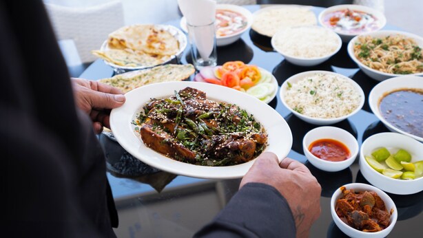 A table set with various dishes, including rice, soup, and a plate of meat. - Monarch Guestline Magarpatta (Pune)