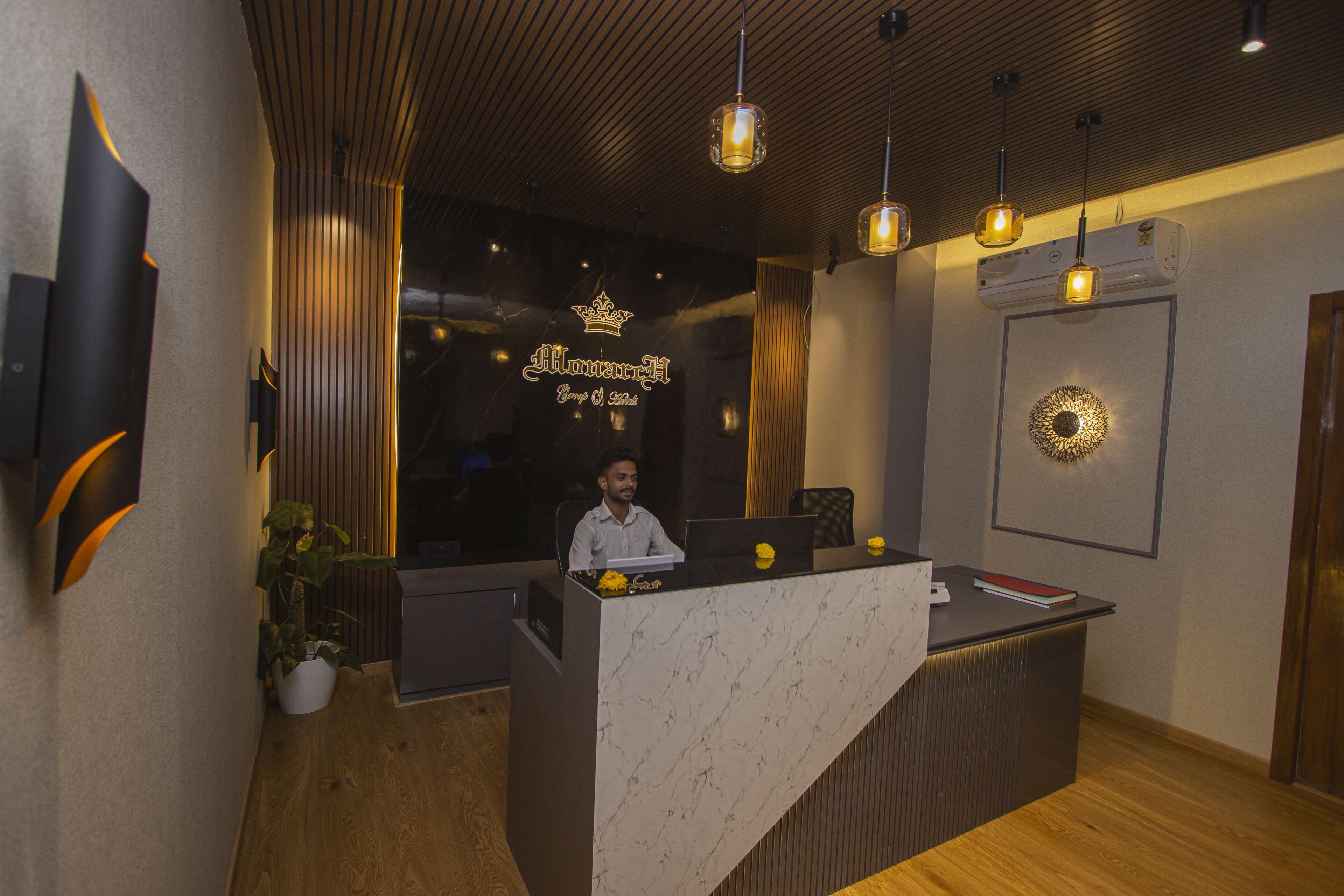 A reception desk with a marble top, a crown logo, and a person seated behind it.
