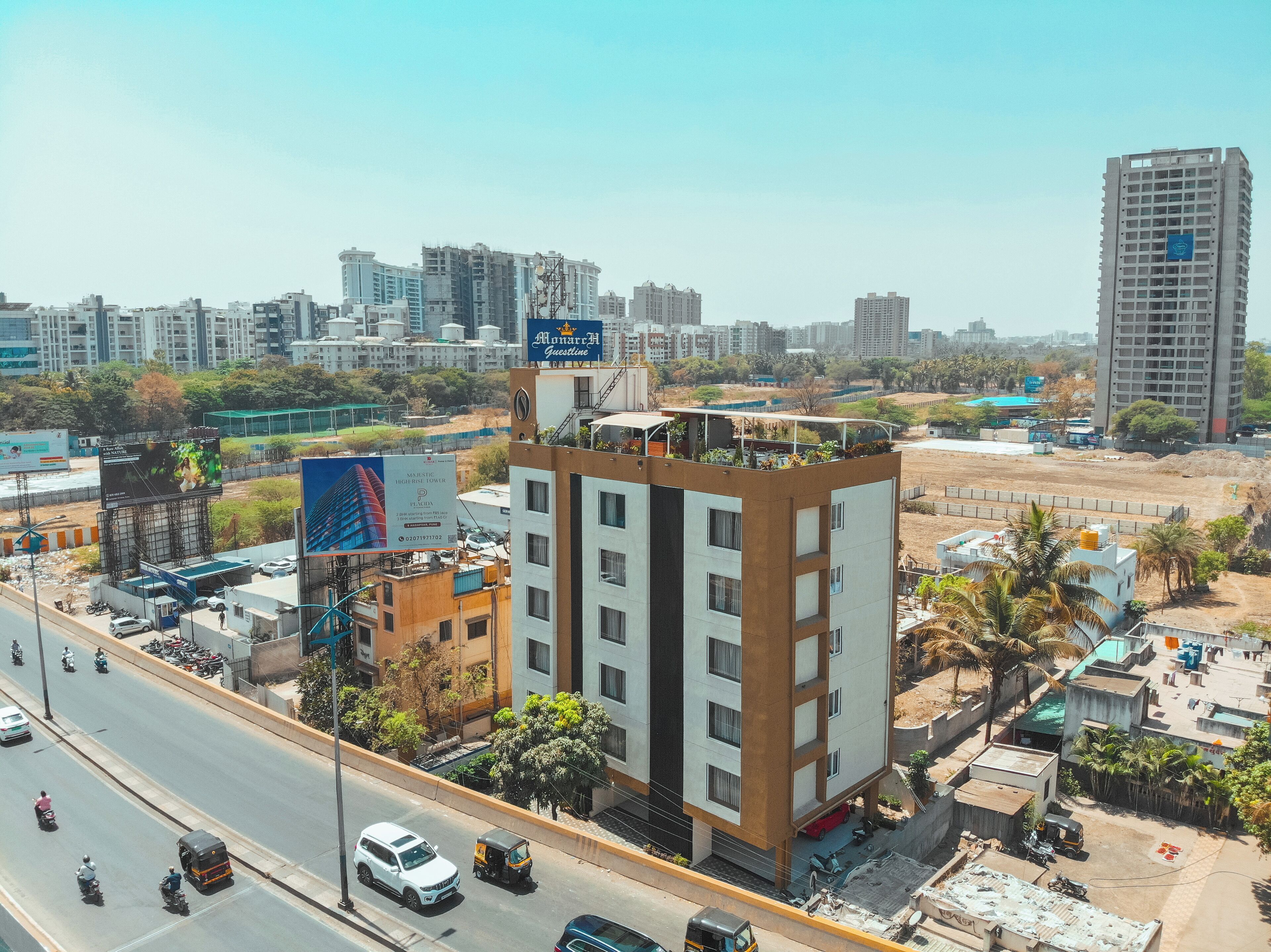 A multi-story building with a flat roof, surrounded by a busy street with vehicles and a billboard advertising a hotel.