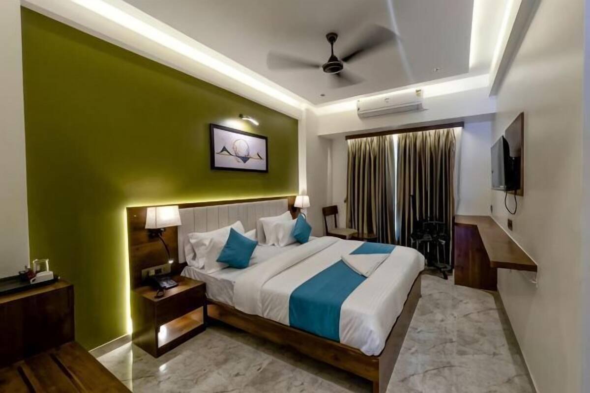 A hotel room with a bed, bedside tables, a ceiling fan, and a window with curtains.