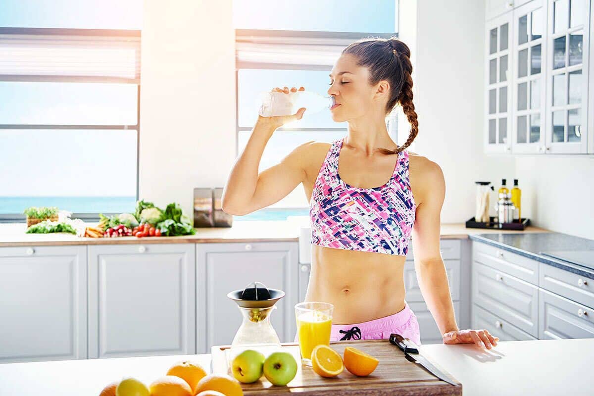 A kitchen with a large window, a fruit bowl, and a juicer.