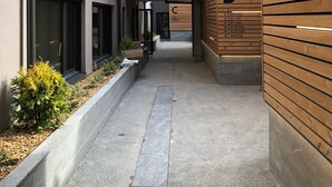 Ein modernes Gebäude mit Holzfassade, einem überdachten Gang und freiem Blick auf den Eingang.