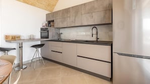 Una cocina moderna con armarios grises, un refrigerador de acero inoxidable y un horno empotrado.