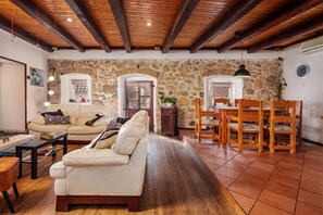 A living room with a sofa, coffee table, and dining table with chairs. - Meja Stone House With Pool (Bakar)
