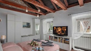 Una camera da letto con un letto, una televisione, una libreria e una finestra con tende.
