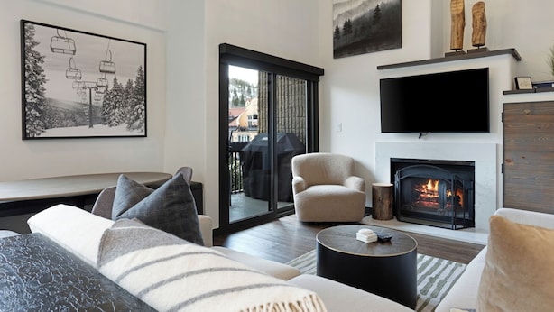 Una sala de estar moderna con chimenea, televisor grande y zona de estar acogedora.
