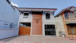 A building with a sign reading "Guest House Laundry Cafe Kosi" and a visible entrance.