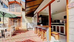 An outdoor seating area with tables and chairs, a bar with stools, and a covered patio.
