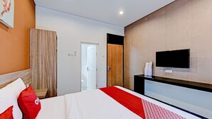 A modern hotel room with a large bed, a TV mounted on the wall, and a wooden wardrobe.