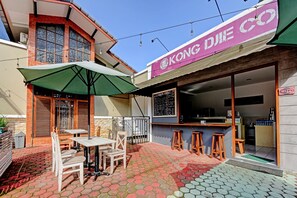 A cafe with outdoor seating, a chalkboard menu, and a pink awning. - Super OYO Capital O 90497 Navaya Guest House (Purwokerto)