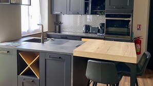 Una cocina moderna con armarios grises, una mesa de comedor de madera y un horno empotrado.