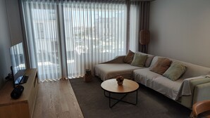 A modern living room with a sofa, a coffee table, and a desk with a laptop.