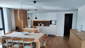 A modern kitchen with white cabinets, a wooden countertop, and pendant lighting.