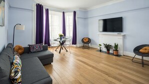 A living room with a sofa, dining table, and TV. - Gloucester Station Gem, 3 Bedroom Oasis (London)