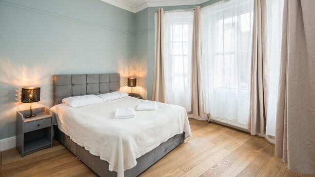A neatly made bed with white linens and two bedside lamps. - Gloucester Station Gem, 3 Bedroom Oasis (London)