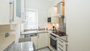 A modern kitchen with granite countertops, stainless steel appliances, and white cabinetry. - Gloucester Station Gem, 3 Bedroom Oasis (London)
