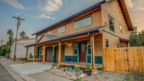 A two-story house with a porch, a garage, and a wooden fence.