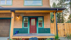 A two-story wooden house with a red front door, a porch with a bench, and a garage door.