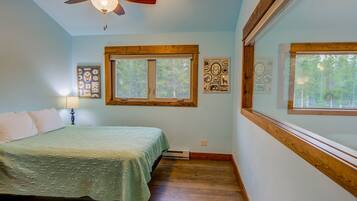 Ein Schlafzimmer mit Bett, Deckenventilator, Fenster und Wandbildern.