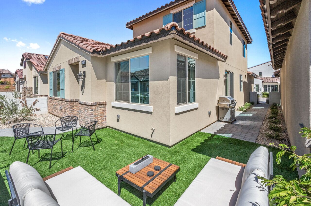 A residential house with a patio area, a small table, and outdoor seating.