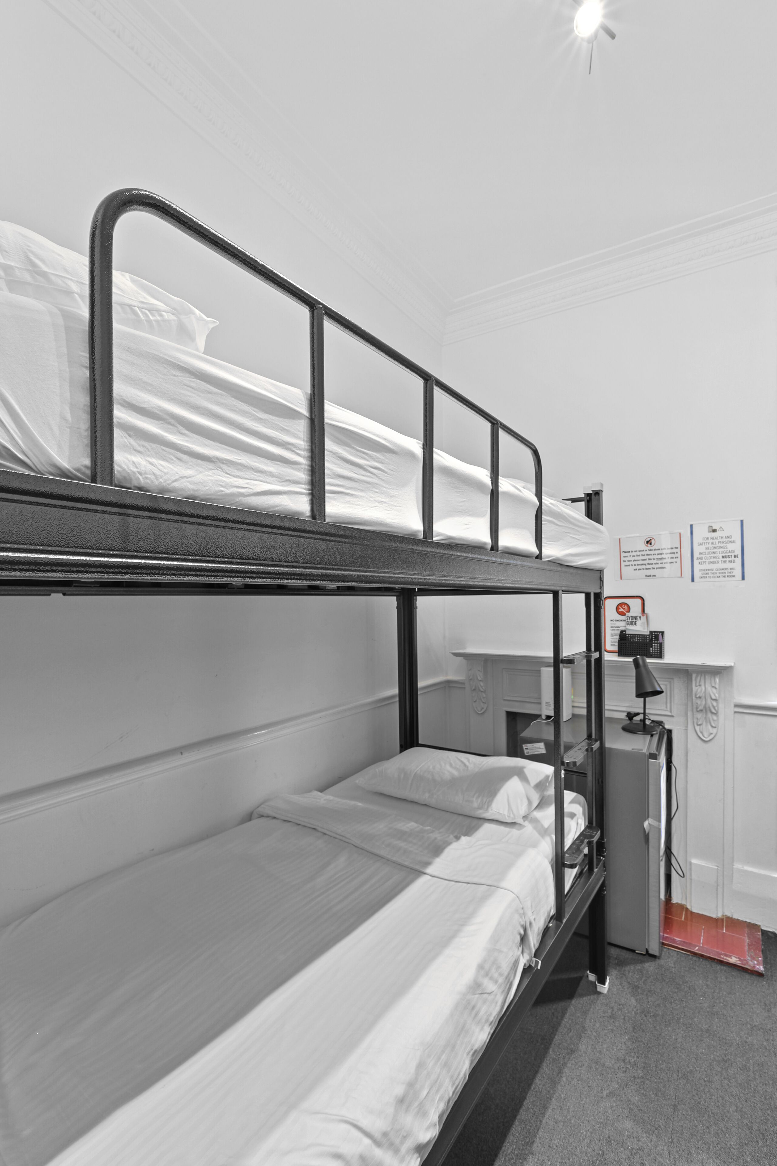 A bunk bed room with a desk and chair, a radiator, and a notice on the wall.
