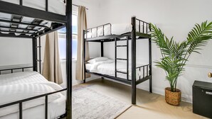 Dormitorio con literas, una planta en maceta y un mueble pequeño.