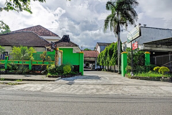 Stroll through a serene garden surrounded by a charming green house with a tiled roof.
