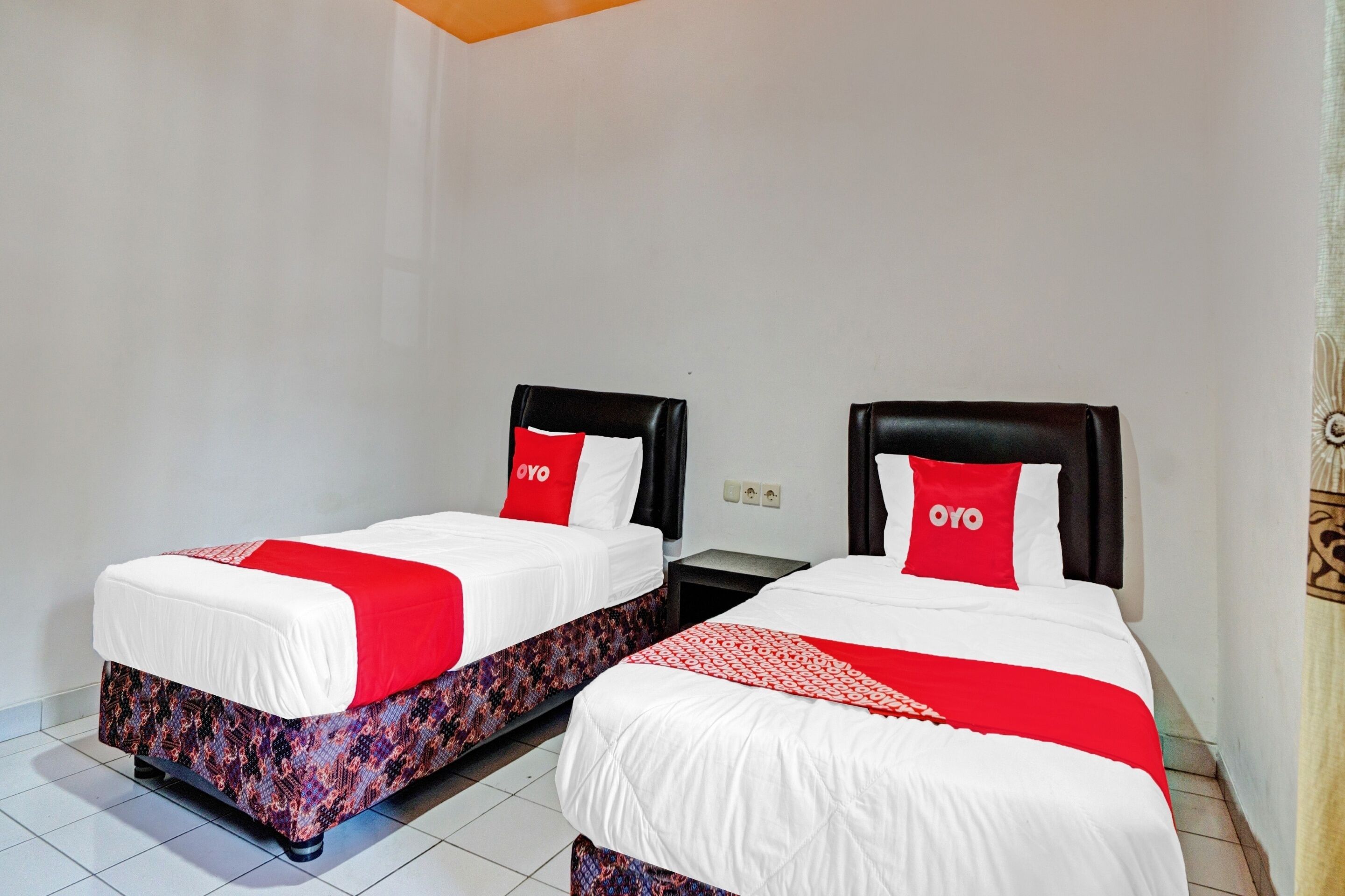 Two single beds with red and white bedding, black headboards, and a patterned bed skirt.