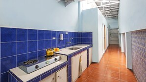 Une cuisine étroite avec des carreaux de céramique bleus, une cuisinière à gaz, un évier et un sol carrelé.