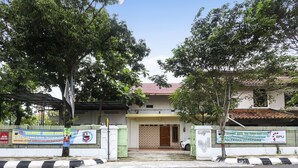 Une maison d’habitation avec une entrée fermée par un portail, un toit en tuiles et une banderole sur le portail.