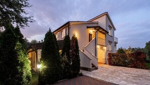A two-story house with a stone pathway leading to the entrance, surrounded by greenery and a brick driveway. - Villa with pool, up to 12 people,6 bedrooms, close to the beach, garden, parking (Porec)