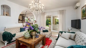 A living room with a chandelier, sofa, ottoman, and a coffee table with flowers. - Villa with pool, up to 12 people,6 bedrooms, close to the beach, garden, parking (Porec)