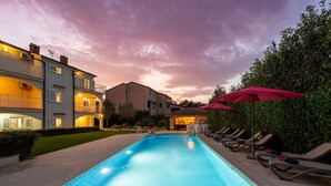 A swimming pool with lounge chairs and umbrellas, surrounded by buildings with balconies and a well-maintained lawn. - Villa with pool, up to 12 people,6 bedrooms, close to the beach, garden, parking (Porec)