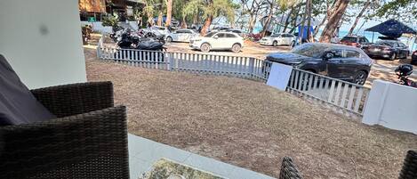 A patio area with wicker furniture, a tiled floor, and a view of parked cars and trees.