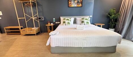 A modern hotel room with a large bed, a wooden ladder, a small table, and a wall-mounted artwork.