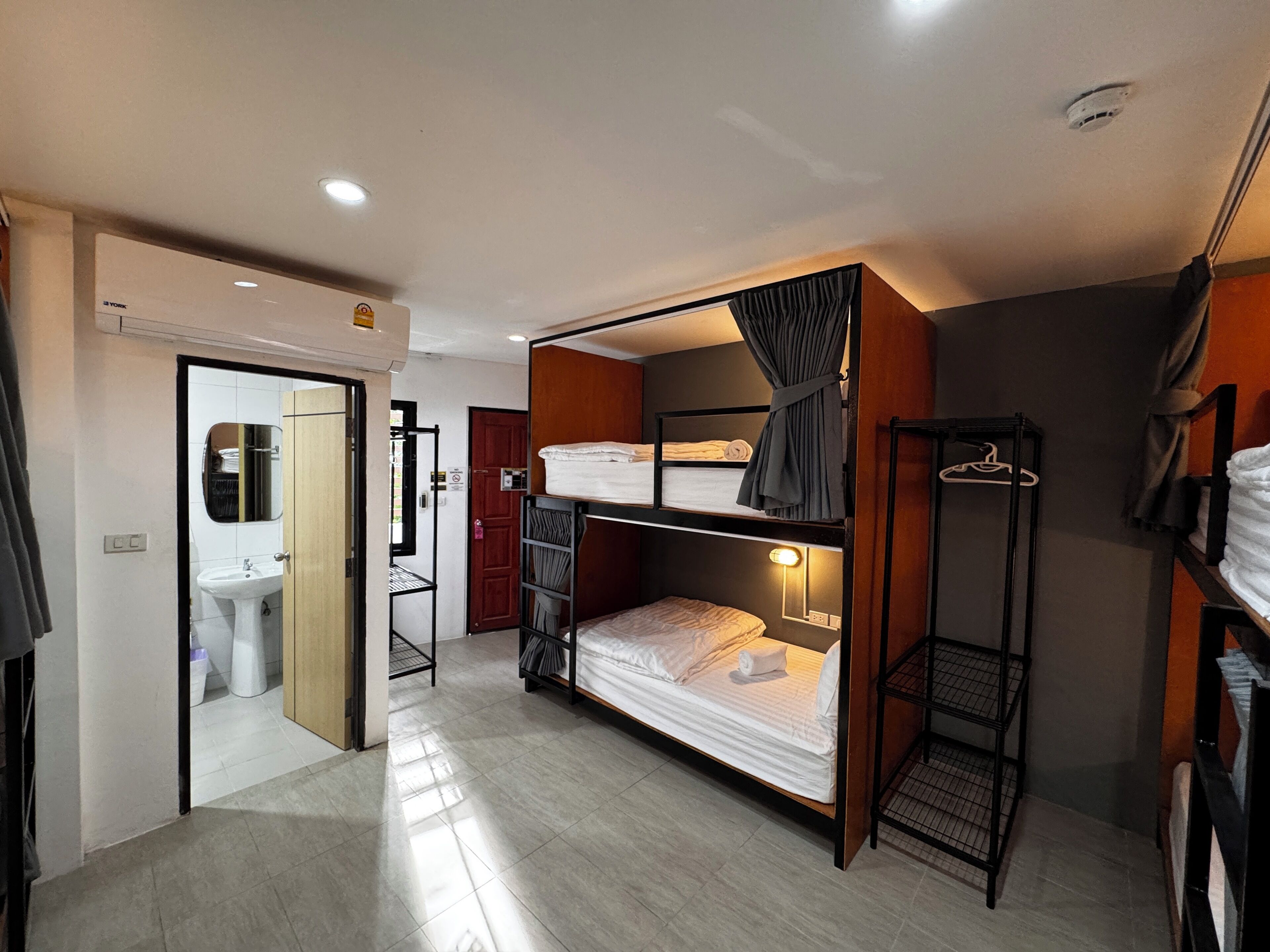 A compact room with a bunk bed, a small bathroom with a sink, and a mirror.