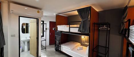 A compact room with a bunk bed, a small bathroom with a sink, and a mirror.