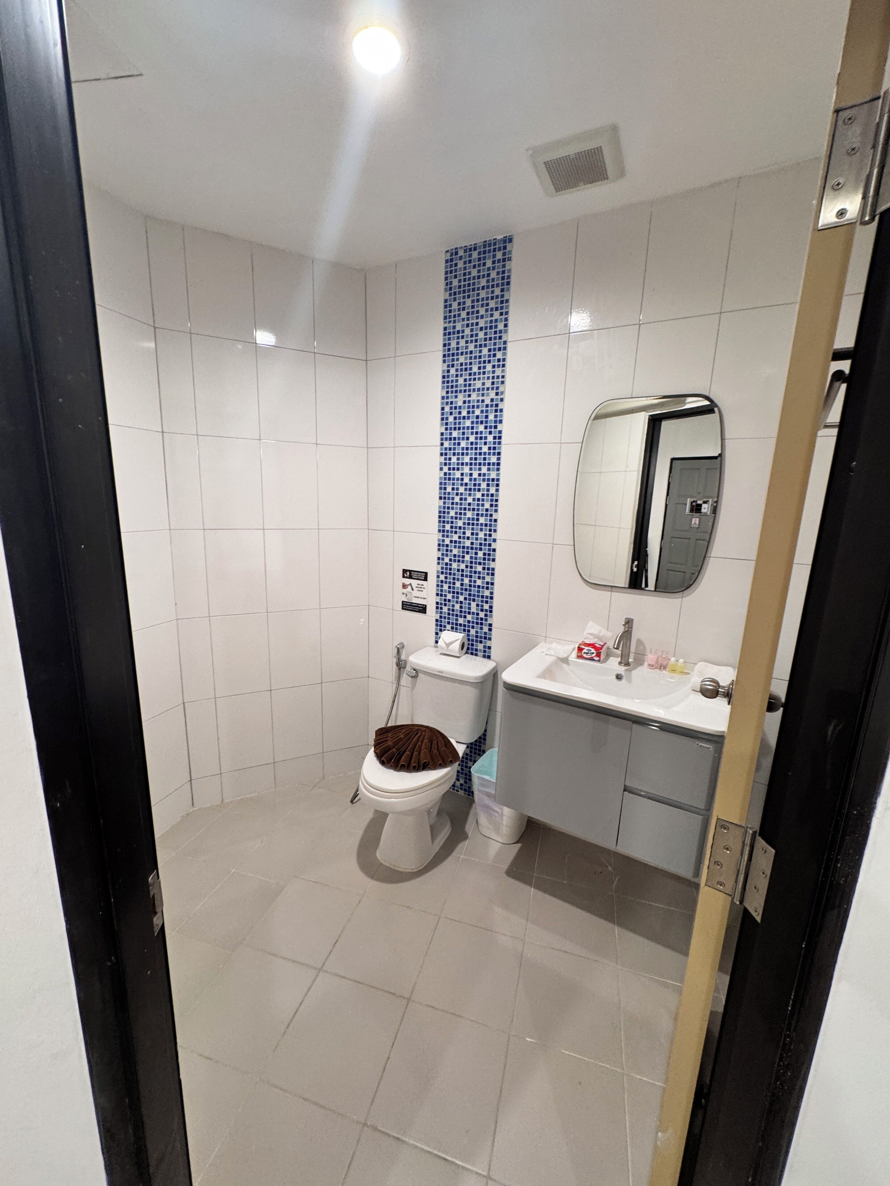 A bathroom with a toilet, bidet, sink, mirror, and tiled walls.
