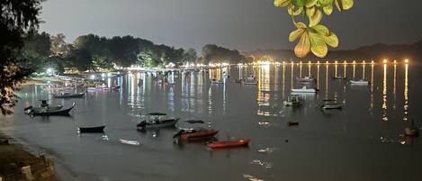 Um calmo areal à noite, com barcos atracados e iluminados por luzes.