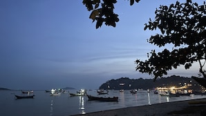 A calm harbor at dusk with boats anchored and lights reflecting on the water. - Phuket Muay Thai Hotel Rawai Beach (Rawai)