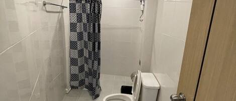 A small, modern bathroom with a toilet, a shower curtain, and tiled walls.
