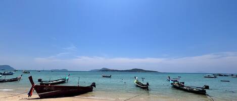 A beach with several boats anchored in the water.