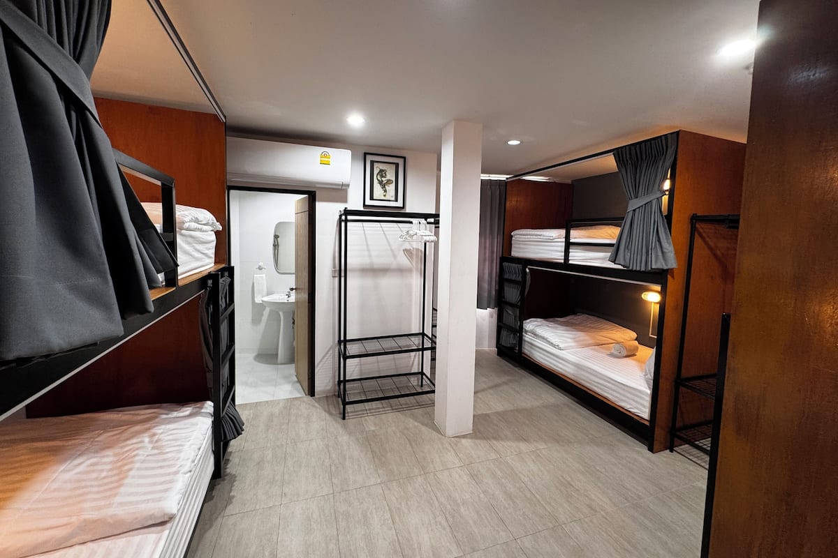 A compact hotel room with bunk beds, a small bathroom, and a neutral color scheme.