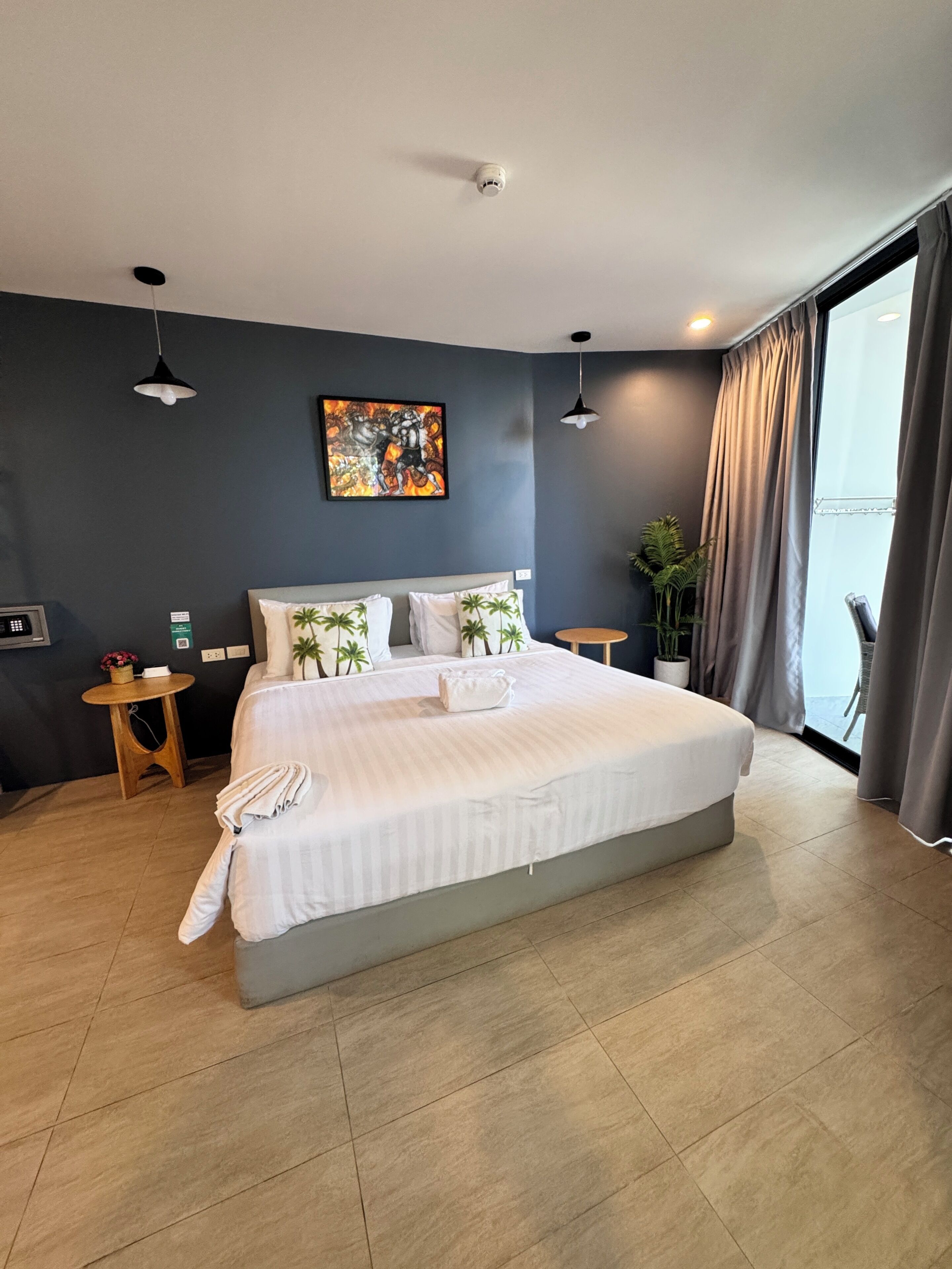 Quarto de hotel moderno com uma cama grande, um quadro na parede e vista pela janela.
