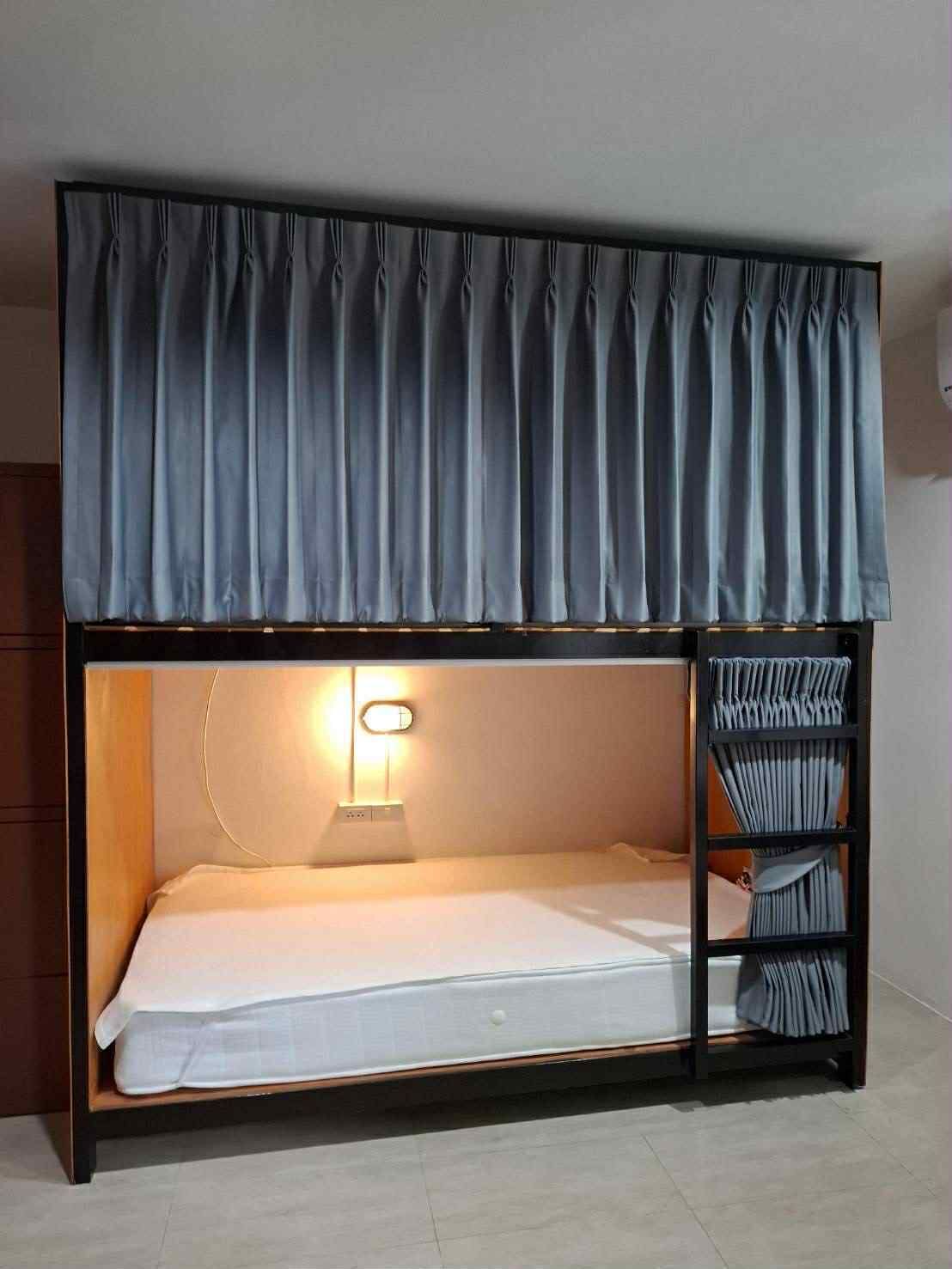 A bunk bed with a headboard, a bedside lamp, and a curtain.