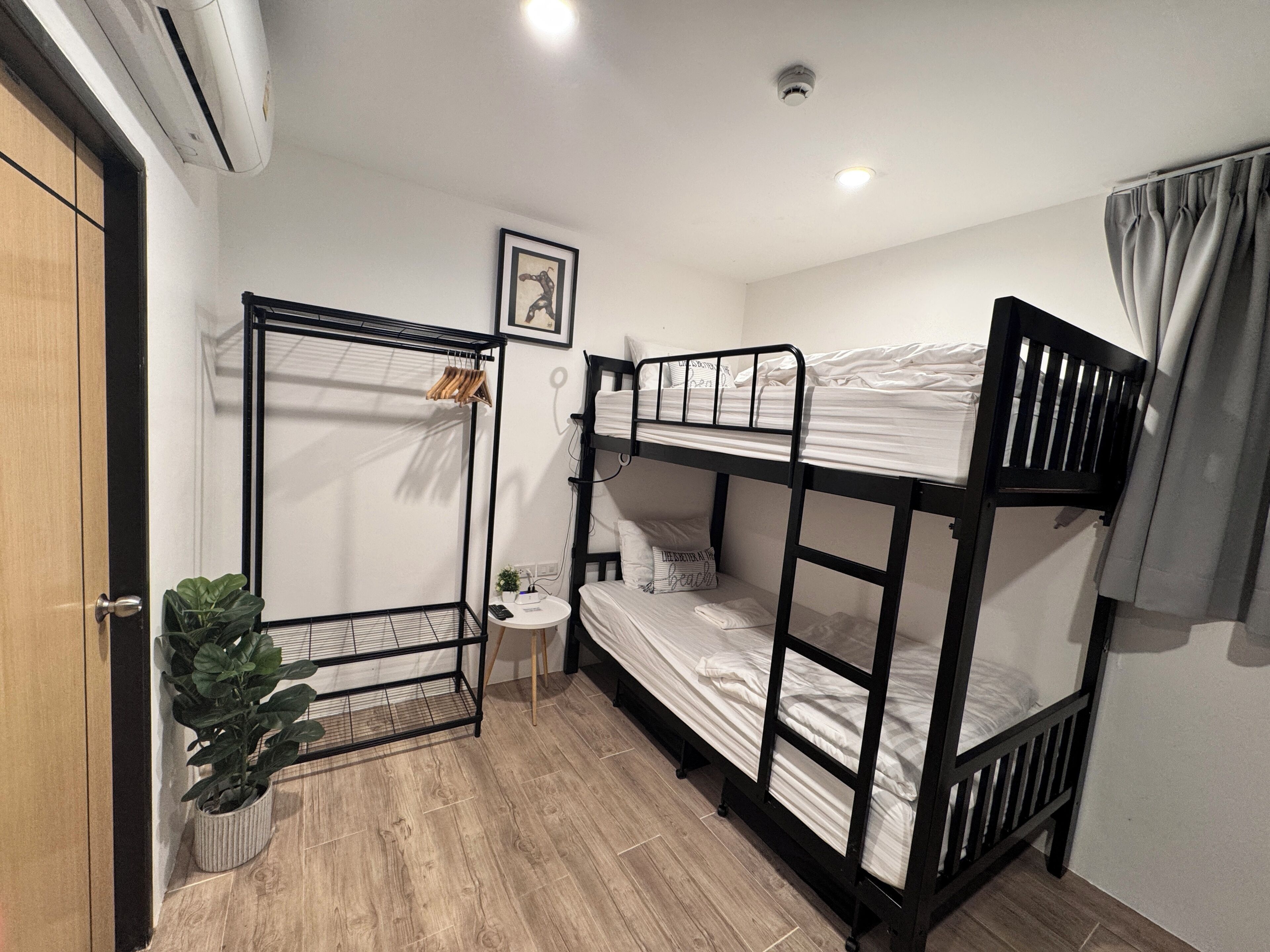 A bunk bed room with a small table, a potted plant, and a framed picture on the wall.