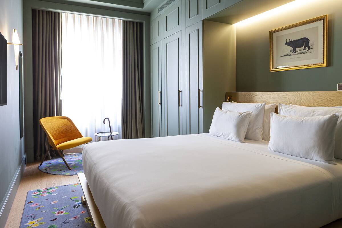 Une chambre d’hôtel avec un grand lit, une chaise, un bureau et une armoire.
