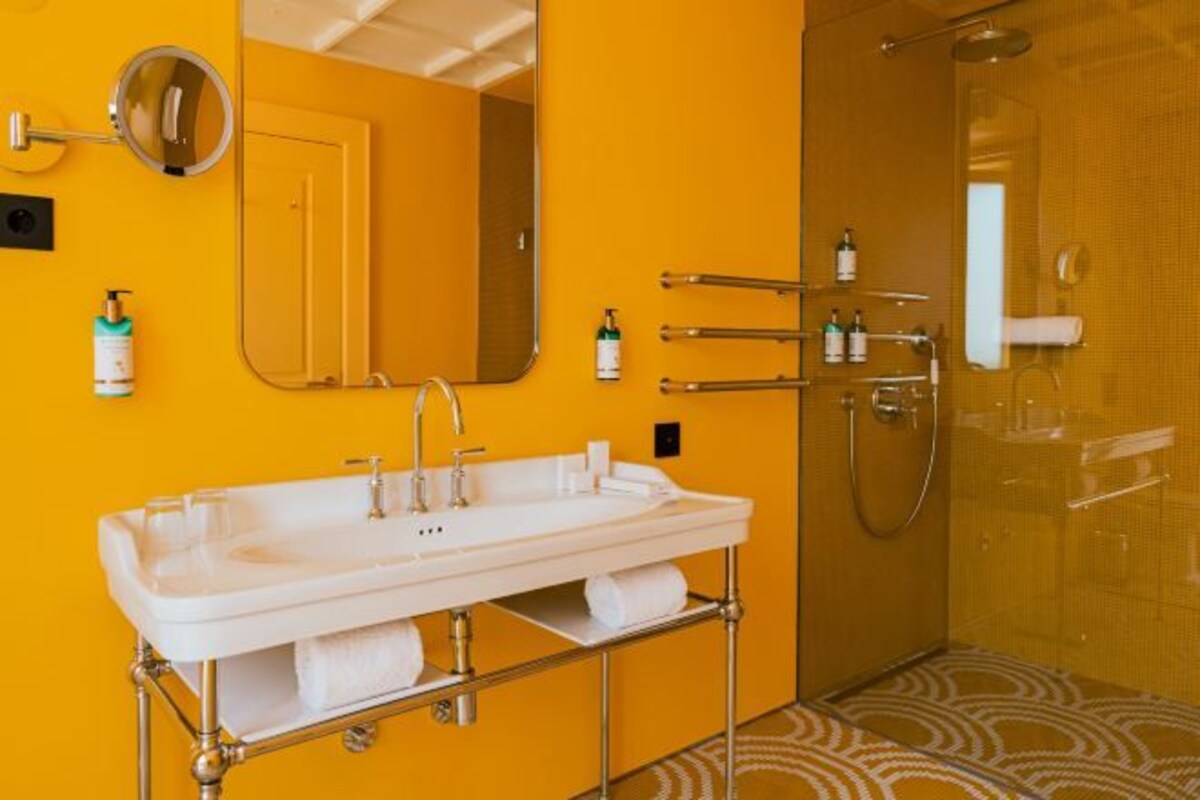 Un baño con lavamanos blanco, un espejo y una cabina de ducha de vidrio.
